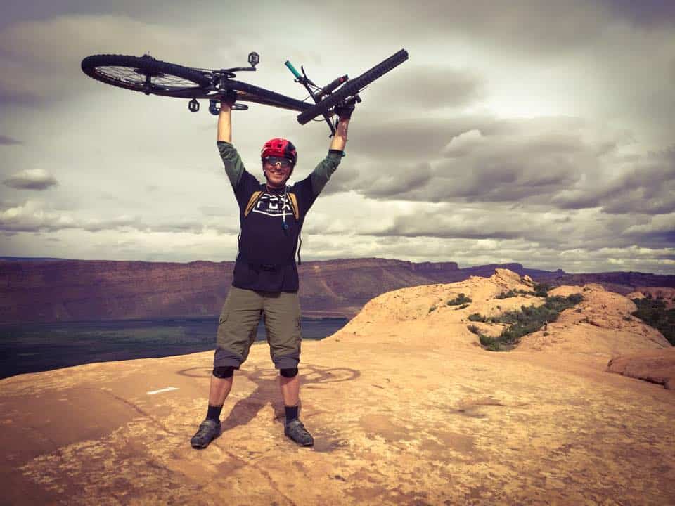 Alex Bogusky carryying a bike at the top of a mountain