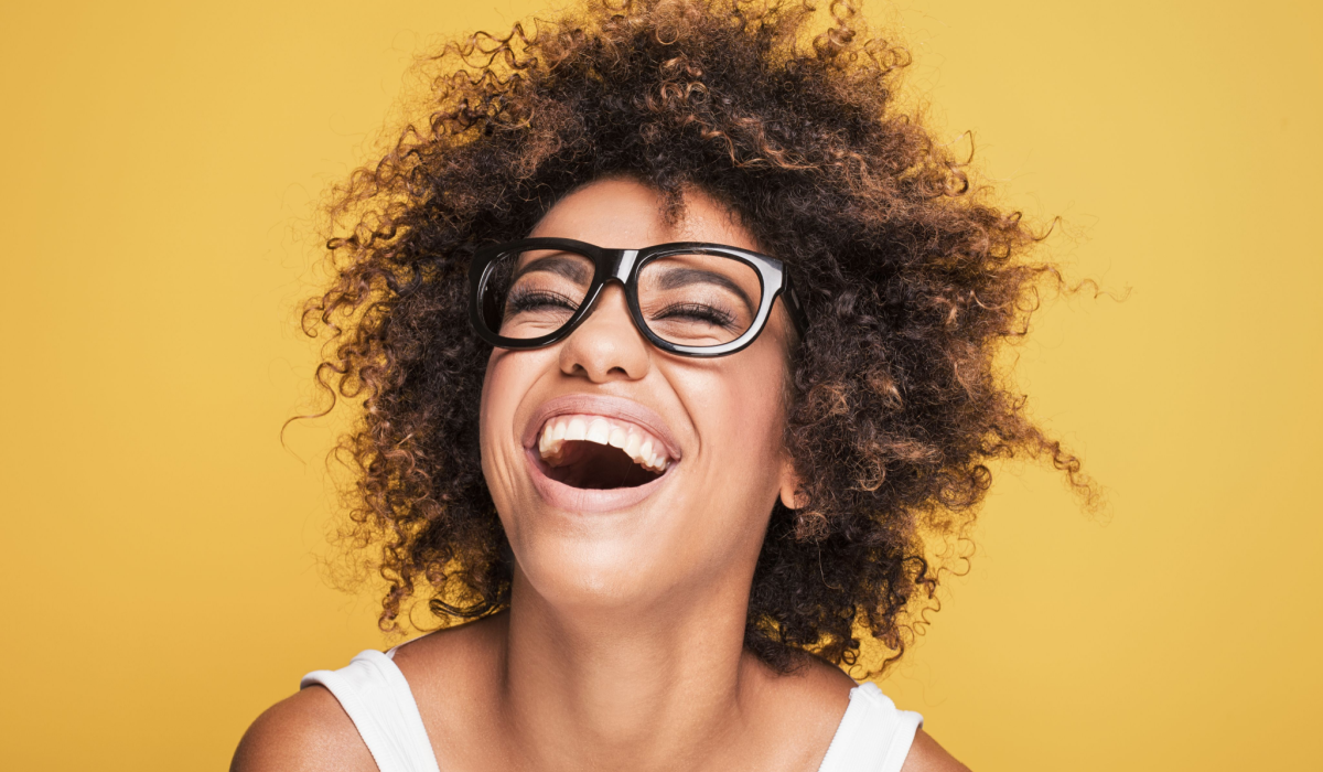 Woman smiling with glasses yellow backdrop